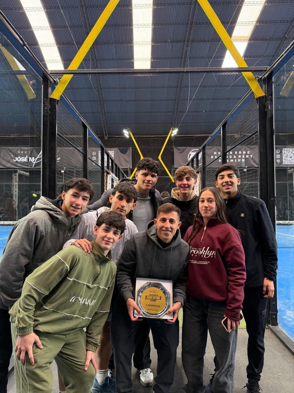Andrés Turaglio junto a un grupo de jóvenes jugadores de pádel con un trofeo de campeón